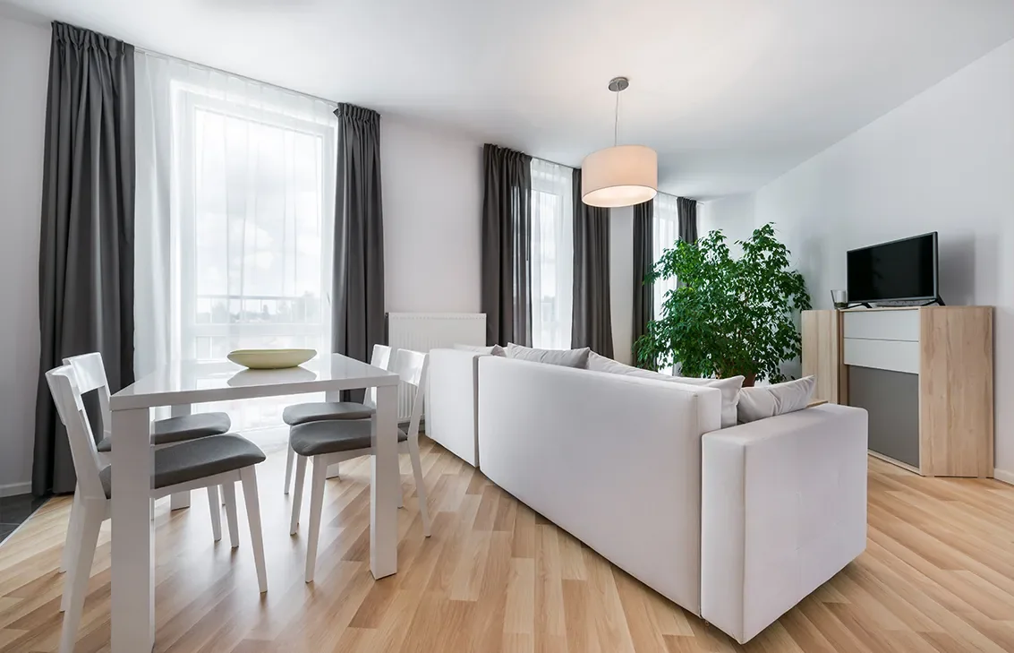 Bright contemporary living room with large windows and soft white furnishings