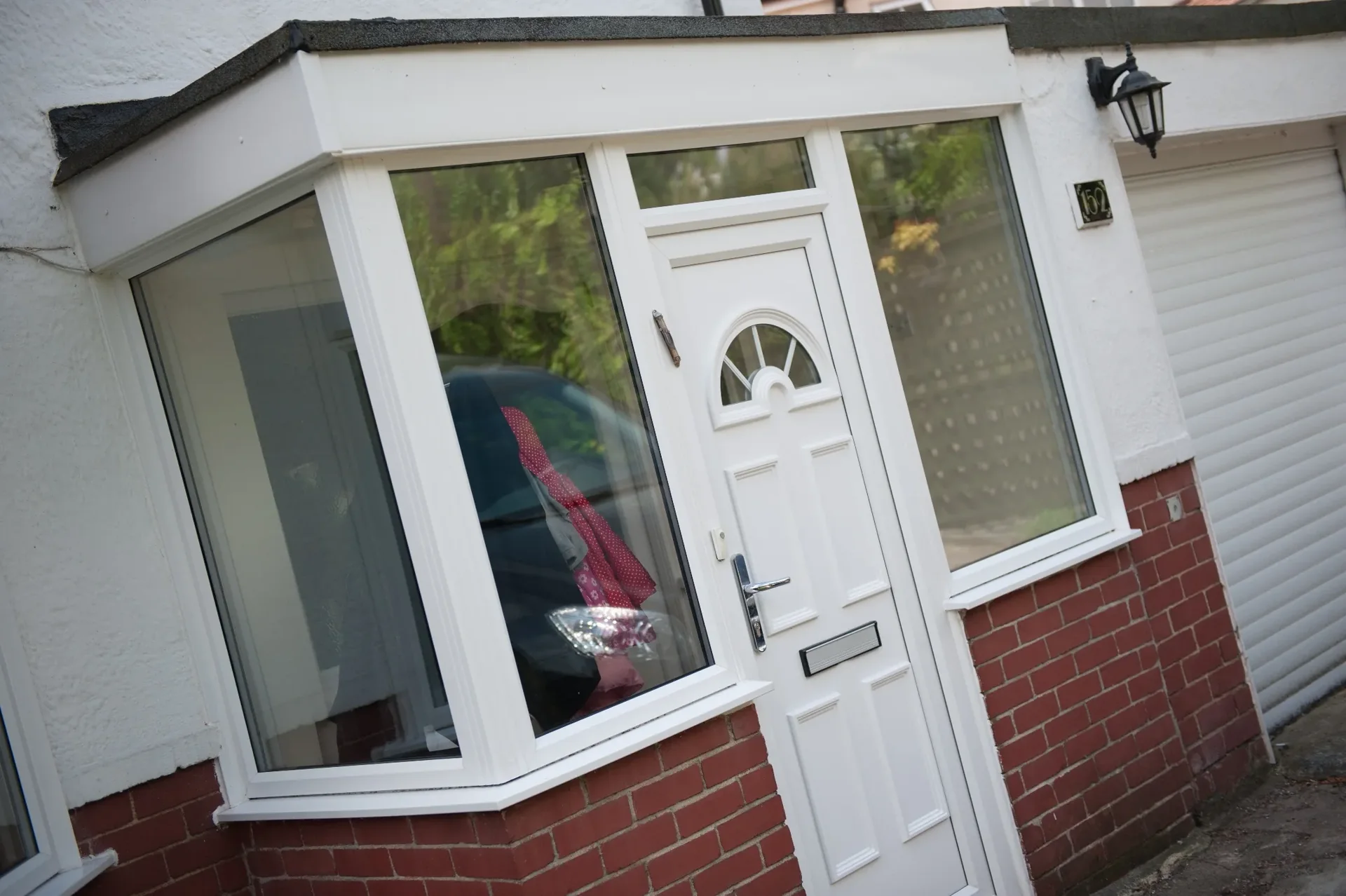 Enclosed white porch with glazed side panels and an arched glazed front door